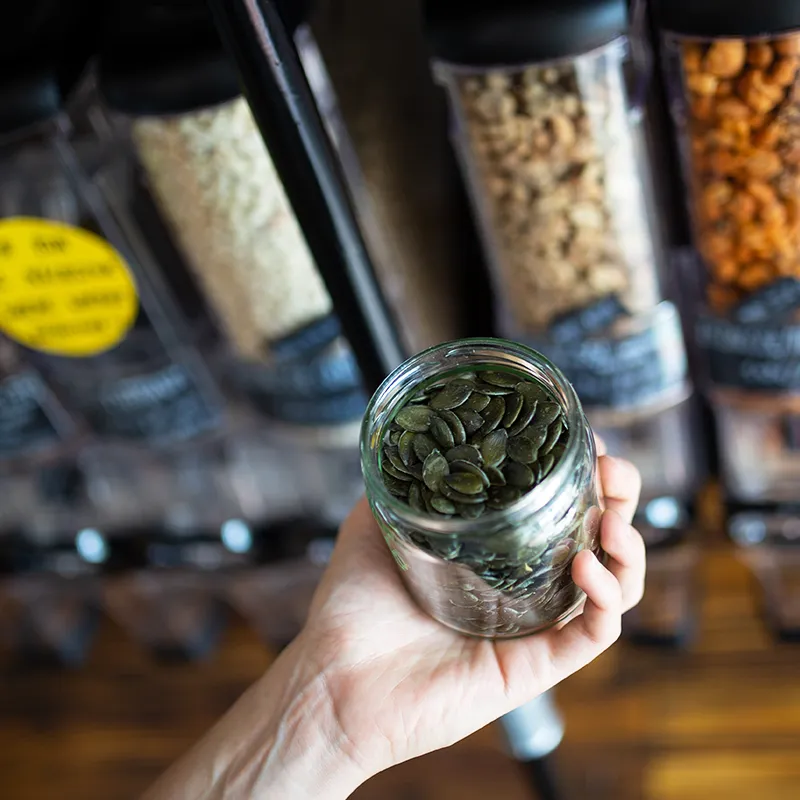 Preserving jar with pumpkin seeds while shopping at the Unpacked store