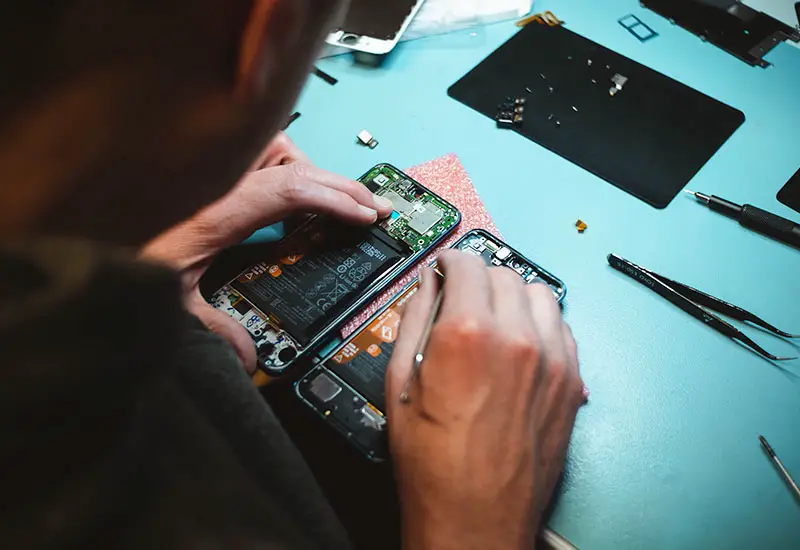 Mann repariert Smartphone am Tisch