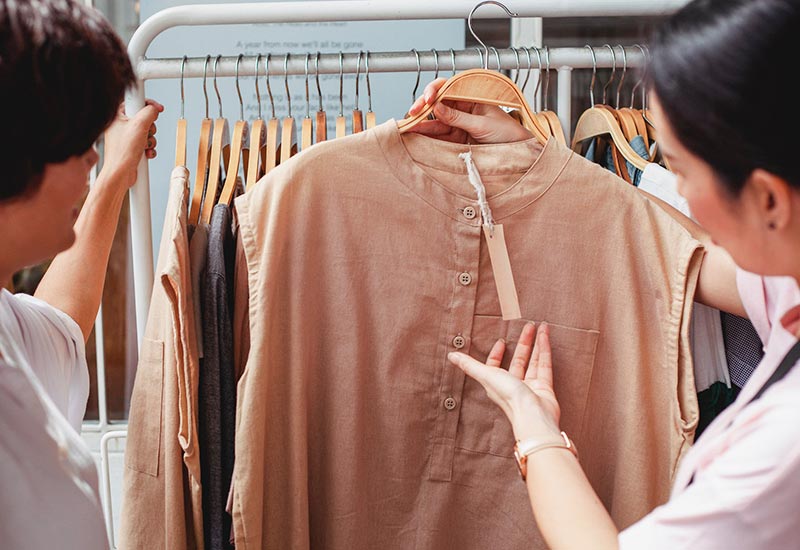 Kleidungsmaterial anfassen und Verkäufer:innen fragen