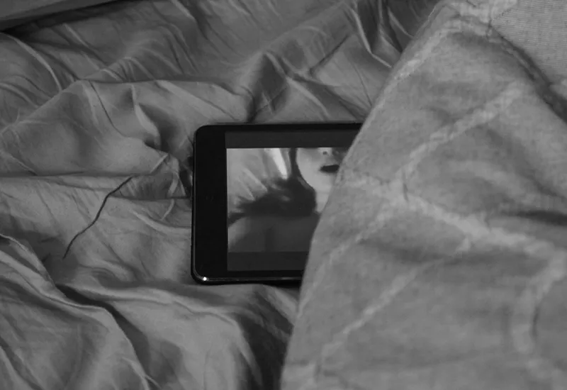 Stöhnende Frau auf einem Smartphone-Bildschirm im Bett