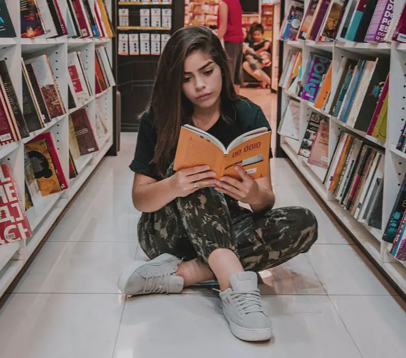 Studentin liest in Bücherei auf dem Boden